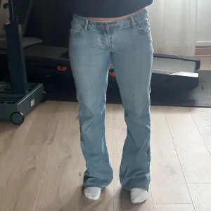 Ljusblå jeans från Visson - Snygga ljusblå jeans från Visson med en klassisk bootcut-stil. De har en hög midja och är perfekta för en avslappnad look. Jeansen har fem fickor och stängs med dragkedja och knapp.