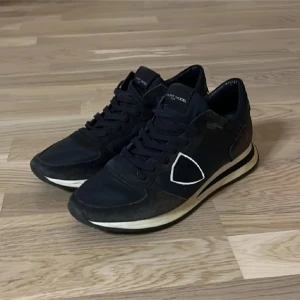 Philippe Model trainers  - Snygga marinblå sneakers från Philippe Model med vita detaljer och snörning. Skorna har en stilren design med en bekväm sula och är perfekta för en casual look. De är i mycket bra skick 8/10