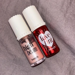 Highlighter och lovetint från Benefit - Två produkter från Benefit: High Beam highlighter i en ljusrosa nyans för en strålande finish och Love Tint läppfärg i en djup röd nyans för intensiva läppar. Perfekt för att skapa en fräsch och livfull look. Highlighter är använd några gånger men liptinten är oanvänd.