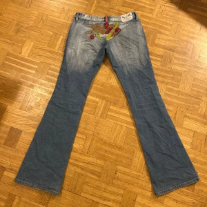 Blå jeans med broderi - Sjukt snygga lågmidjade bootcut jeans som liknar crazy age men kommer från märket ”New crazy” som jag säljer då de inte är min stil längre. De är lite upptrampade på ena hälen, se sista sista bilden.   Mått: 39cm rakt över midjan, 83cm innerbenslängd, 101cm full längd, 17cm grenhöjd och 24cm benöppning  Står storlek L men skulle säga att de mer är som S. Fråga ifall du undrar över något!