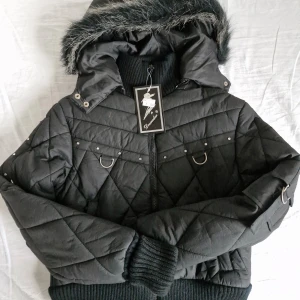 Svart jacka Dromedar - Säljer denna fantastiska jacka från Dromedar 🖤 Svart modell med pälsluva, långa ribbade muddar, halvpolokrage och markerad midja. Utsmyckad med små stenar. Även två fickor framtill. Stängs med dragkedja. Luvan kan tas av, alltså två jackor i en! Finns några små skavsår från frakt, se de sista tre bilderna. I övrigt är jackan i nyskick :)  Pris är självklart förhandlingsbart 😊