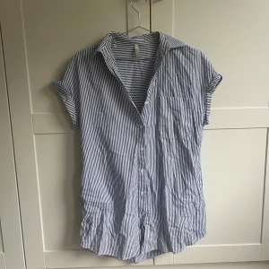 Blå- och vitrandig skjorta från Zara - Säljer en blå- och vitrandig klänning/skjorta från Zara med korta ärmar och knappar framtill. Skjortan har en avslappnad passform och en klassisk krage. Perfekt för en somrig look! Säljer för 130kr + frakt 💫🫶🏻🌸