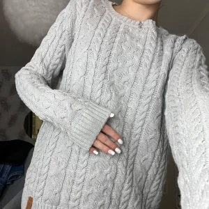 Grå stickad tröja från 157 - Säljer en mysig grå stickad tröja från 157 med klassiskt flätmönster. Tröjan har långa ärmar och ribbstickade muddar vid ärmslut och nederkant. Perfekt för kyliga dagar! Den kostade 150 kr när jag köpte den. Den är använd runt 2 gånger så den är som ny. Super fin och super skön! 😍