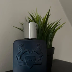 Layton Eau de Parfum från Parfums de Marly - Säljer en elegant flaska av Layton Eau de Parfum från Parfums de Marly. Flaskan är mörkblå med en stilren design och har en silverfärgad kork. Den rymmer 125 ml och är tillverkad i Frankrike. Perfekt för den som söker en lyxig doftupplevelse. Öppen för byten.