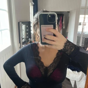 Svart långärmad topp med spetsdetaljer - Snygg svart långärmad topp med v-ringad spetsdetalj.