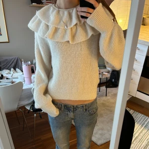 Vit stickad tröja med volang - Superfin vit stickad tröja med volangdetaljer runt halsen. Köpt i strl L då jag ville ha den lite större, men syns på bilderna hur den sitter på mig som vanligtvis är s💕Aldrig använd!