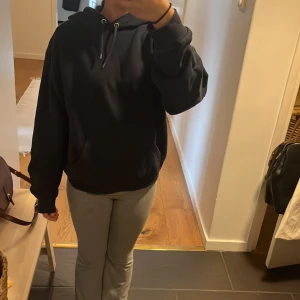 Mörkblå hoodie från Monki - Säljer en klassisk svart hoodie med dragsko i huvan. Tröjan har långa ärmar och en bekväm passform, perfekt för en avslappnad stil. Passar bra till både jeans och träningsbyxor.