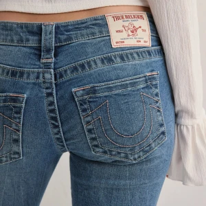 Blå jeans från True Religion - Säljer mina helt nya true religion jeans från Nelly. De är uppsprättade en söm längst ner i benen och passar i längden för mig som är 1,74🥰 Säljer då jag inte tyckte att de satt fint på mig, skriv för bilder på mina jeans💗