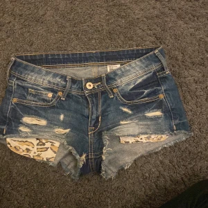 Blå jeansshorts från H&M - Snygga blå jeansshorts från H&M med slitna detaljer och leopardmönstrad insida. Perfekta för en cool och avslappnad stil. Shortsen är lågmidjade!💕