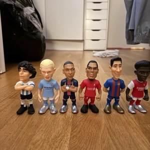 Fotbollsfigurer i plast - Säljer en samling av sex fotbollsfigurer i plast. Varje figur har en unik fotbollsdräkt med olika färger och nummer på ryggen. Perfekt för fotbollsfans som vill ha en rolig dekoration eller samlarobjekt.