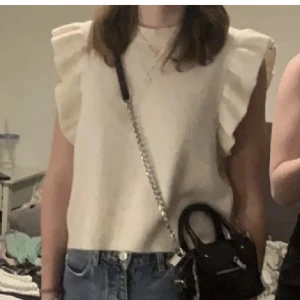 Vit ärmlös topp från Noisy May - Säljer en stilren vit ärmlös topp från Noisy May. Toppen har volangdetaljer vid axlarna och är tillverkad i ett mjukt material. Den har bara används fåtal gånger så den är så gott som i nyskick! Priser går att diskutera🩷