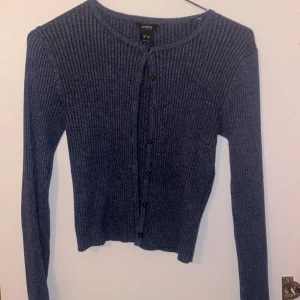 Blå ribbad kofta från Lindex - Snygg blå ribbad kofta från Lindex med knappar framtill. Perfekt för kyligare dagar med sin långärmade design. Enkel och stilren, passar till många olika outfits. LÄS: Jar ett litet hål vid nacken.  Men skulle säga att det är lätt lagat 💕