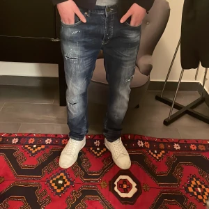 Goldgarn Jeans - Ett par feta goldgarn jeans med färg spläsch och slitningar | storlek 34W/32L | Modellen är 190cm | Fast pris