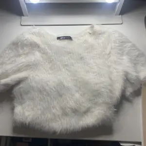 Superfin vit fluffig tröja från Gina Tricot! Den är kortärmad och croppad, perfekt för en cool och mysig look. 🐑✨