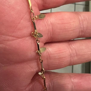 Fotband - Säljer ett elegant guldarmband med små ovala detaljer. Armbandet har en fin glans och är perfekt för både vardag och fest. Det är lätt och bekvämt att bära, med en säker låsning. Passar perfekt som en stilren accessoar till vilken outfit som helst.