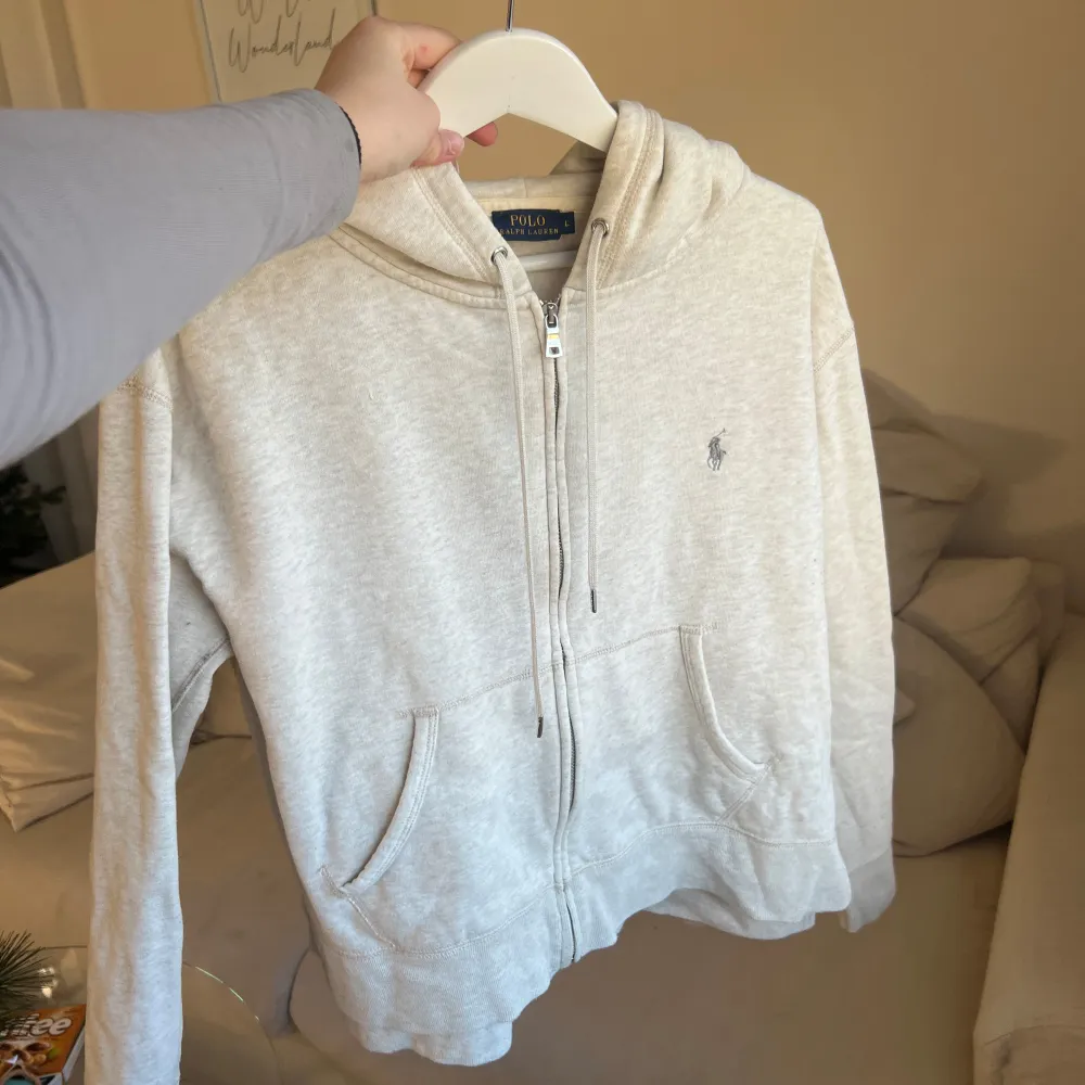 Säljer en snygg beige hoodie från Polo Ralph Lauren i storlek L. Den är i mycket bra skick och har en dragkedja framtill samt en klassisk logga på bröstet. Perfekt för höst och vår, och den är supermjuk och bekväm. Passar både till vardags och chillkvällar. 🧥✨passar både herr och dam. Passar även en M. Köpt för 2499kr. Tröjor & Koftor.