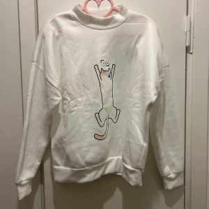 Vit sweatshirt med kattmotiv - Säljer en supermjuk vit sweatshirt med ett gulligt kattmotiv på framsidan. Kan finnas spår av katthår