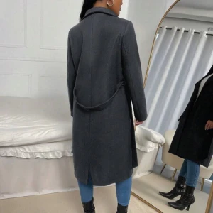 Grå kappa med knytband - Snygg grå kappa i ull med knytband i midjan. Perfekt för höst. Den har en elegant krage och långa ärmar, vilket gör den både stilren och varm. Passar perfekt till både vardag och fest!