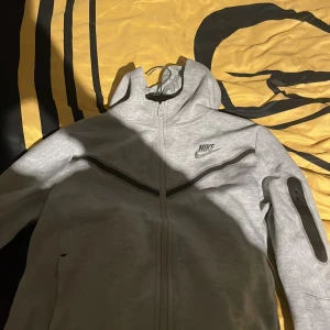Grå hoodie från Nike - Säljer en grå hoodie från Nike i storlek 147-158. Den har en dragkedja framtill och en cool ficka på ärmen. Perfekt för höst och vår, och den är i mycket bra skick. Superbekväm och stilren.