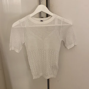 Vit stickad topp från H&M Divided - Säljer denna topp som funnits i H&Ms sortiment för cirka 5 år sen men har bara legat i en låda sedan dess. Prislappen sitter inte kvar då jag har tvättat den för att sälja den.  