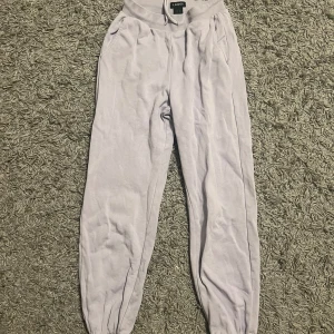 Ljuslila mjukisbyxor från Lindex - Superbekväma ljuslila mjukisbyxor från Lindex i storlek S. Perfekta för en chill dag hemma eller en snabb tur till affären. De har en elastisk midja med snörning och muddar vid bensluten för extra komfort. Materialet är mjukt och skönt, vilket gör dem till ett måste i garderoben!