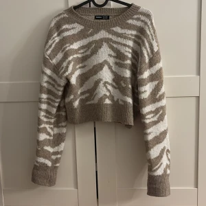 Beige och vit zebramönstrad tröja - Säljer en superfin beige och vit zebramönstrad tröja. Den är croppad och har långa armar, perfekt för höst och vinter. Tröjan är i mycket bra skick och gjord av ett mjukt material som känns skönt mot huden. 