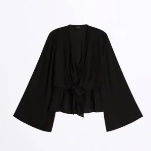 Svart blus med knytning - Snygg svart blus med knytning framtill och vida ärmar. Perfekt för både vardag och fest. Den har en lös passform som ger en avslappnad men stilren look.
