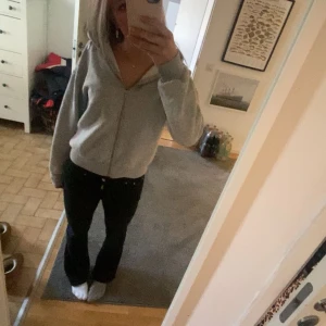 Grå hoodie med dragkedja - Mysig grå hoodie med dragkedja framtill. Perfekt för kyliga dagar eller mysiga hemmakvällar. Den har en luva och långa ärmar, vilket gör den extra bekväm och varm. Passar bra till jeans eller mjukisbyxor för en avslappnad look.