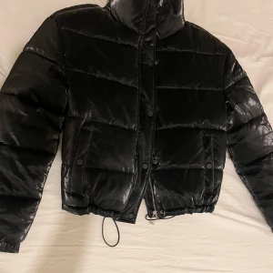 Svart pufferjacka - Säljer en snygg svart pufferjacka som är glansig helt oanvänd har bara hängt i garderoben, pris kan diskuteras vid snabb affär 