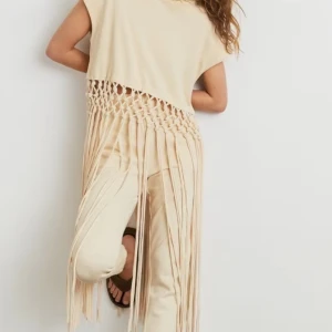 Beige fransklänning med fransar - Säljer en unik beige fransklänning med fransar. Den är ärmlös och har en cool bohemisk stil, perfekt för sommaren. Klänningen är i bra skick och passar perfekt till festivaler eller en dag på stranden. Ny, endast provad, dock liiite smink på kragen. Har rökfritt hem men har hund. 