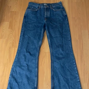 Blå utsvängda jeans från Natura - Säljer ett par snygga blå jeans från Natura i storlek 38. Med knappgylf. Ganska tighta i storleken men coola om du vill ha en 70-talslook😎