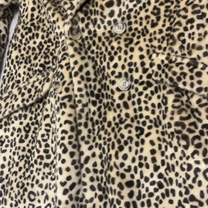 Leopardmönstrad pälsjacka s/m - Säljer en supercool leopardmönstrad pälsjacka i mycket bra skick. Den har långa ärmar och knappar framtill, samt ett bälte i midjan för en snygg passform. Perfekt för höst och vinter när du vill sticka ut lite extra!