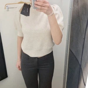 Beige kortärmad tröja med puffärm - Säljer en superfin beige tröja med korta puffärmar. Den är i ett mjukt material och har en ribbad kant vid midjan! 🥰