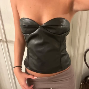 Svart skinn korsett - Snygg svart axelbandslös korsett i skinnimitation. Helt ny!