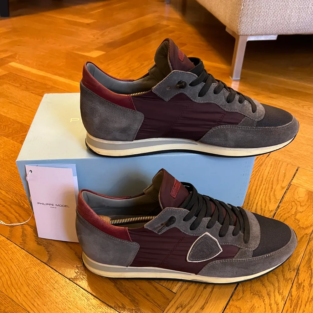 Snygga Philippe Model sneakers i grått och vinrött. De har en stilren design med snörning och en bekväm sula. Perfekta för både vardag och fest. Skorna är i mycket bra skick och kommer med originalkartong.. Skor.