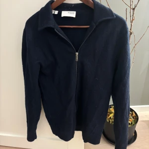 Merinoull overshirt  - Säljer en snygg mörkblå merinoulls overshirt från Selected Homme i storlek S. Tröjan har en praktisk dragkedja framtill och är perfekt för både höst och vinter. Den är långärmad och gjord i ett mjukt material som håller dig varm. Perfekt för en stilren look!