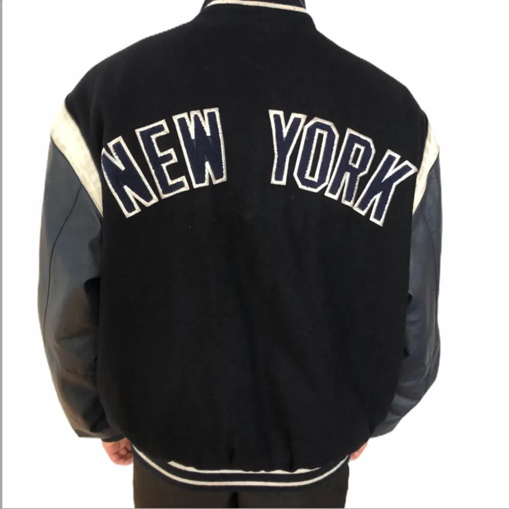 Säljer en sällsynt vintage svart bomberjacka från Jeff Hamilton med New York Yankees-logga. Jackan har långa ärmar och knappar framtill. Den är gjord av polyester och läder, perfekt för höst och vår. Den är även reversible så man kan ha den på två sätt!                                                                    Yankees-märke på ärmen och text på ryggen ger en sportig look. Passar perfekt för casual outfits!  Perfekt för collectors!. Jackor.