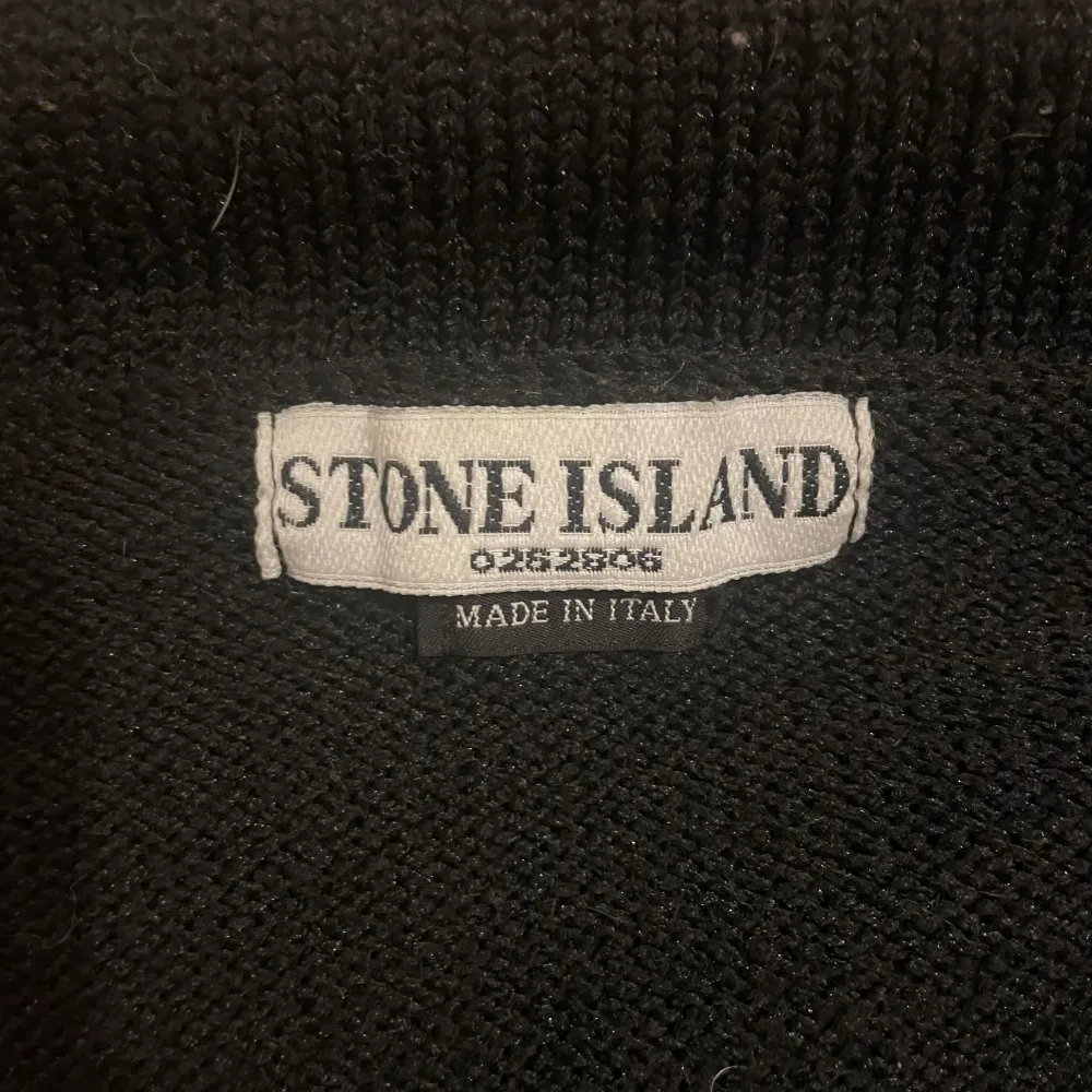 Säljer en snygg svart tröja från Stone Island med grå detaljer längs ärmarna. Tröjan har en dragkedja framtill och en hög krage för extra stil och värme. Perfekt för höst och vinter! Den ikoniska Stone Island-loggan sitter på vänster ärm. Passar både till vardags och lite finare tillfällen. . Tröjor & Koftor.