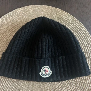Svart ribbad mössa från Moncler - Säljer en snygg svart ribbad mössa från Moncler. Den är i mycket bra skick
