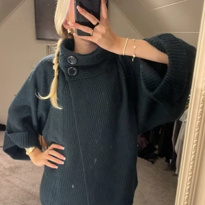 ull kofta - Säljer en supermysig mörkgrön stickad tröja med stora knappar vid halsen. Den har en loose passform och trekvartsärmar, perfekt för höst och vinter. Tröjan är i mycket bra skick och passar perfekt för en avslappnad stil. Perfekt för att mysa i hemma eller på en kylig promenad!