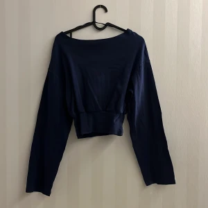 Gina Tricot Topp - Topp i ribbad trikå med utsvängda ärmar. Toppen är blå och har båtringning. Den har lös passform och figurnära midja med rynkningar.