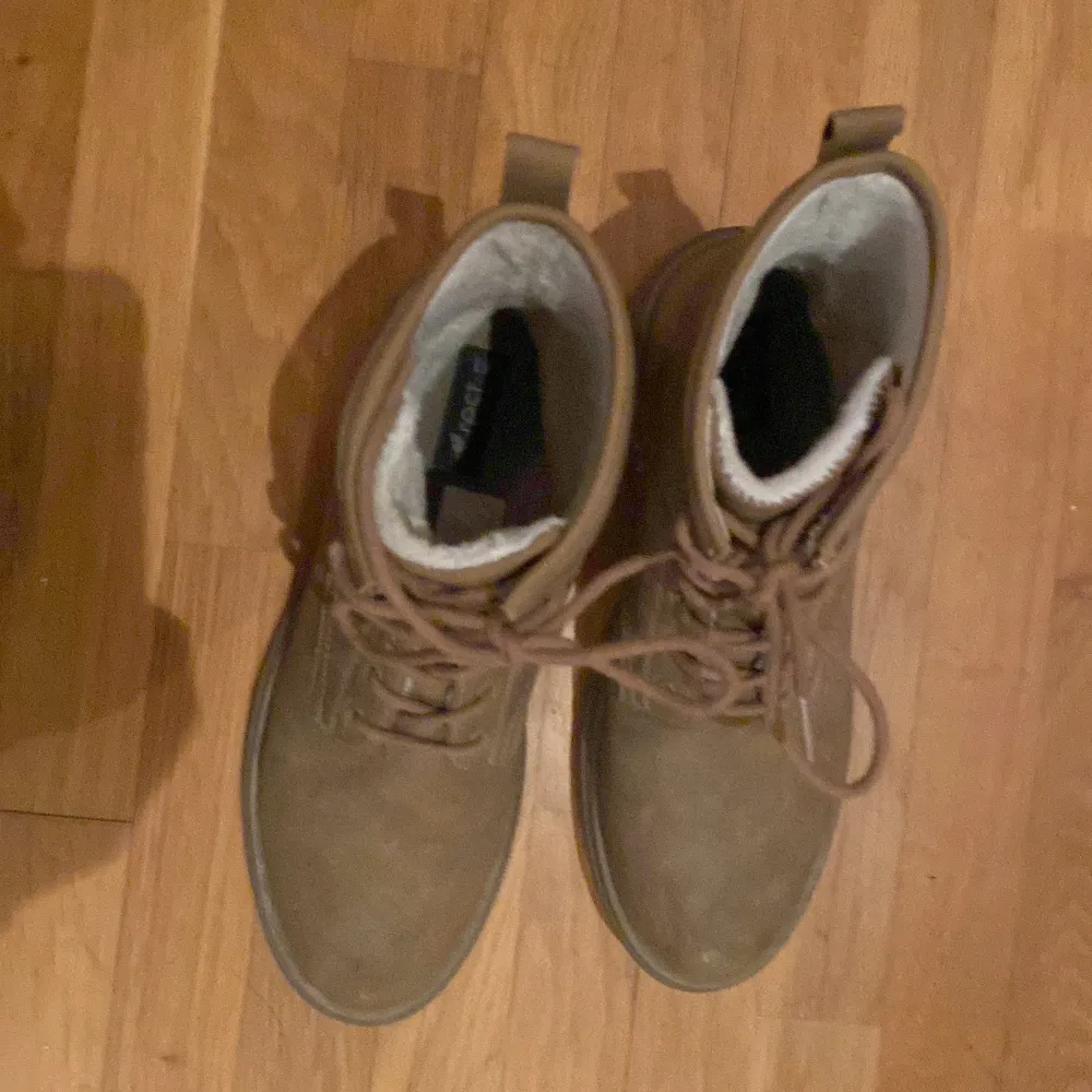 Säljer ett par bruna boots från Rest i bra skick. De är i storlek 41 och har en robust design med snörning framtill. Perfekta för höst och vinter med sitt varma foder. Skorna är tillverkade i ett slitstarkt material som passar för kyligare väder.. Skor.