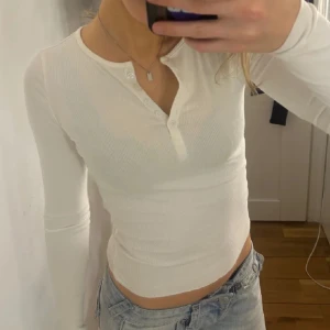 Vit ribbad långärmad topp - Säljer en superfin vit ribbad topp med lång ärm och knappar framtill. Perfekt för både vardag och fest! Skön och stretchig. Hör av dig vid intresse! 💖(lånad bild)