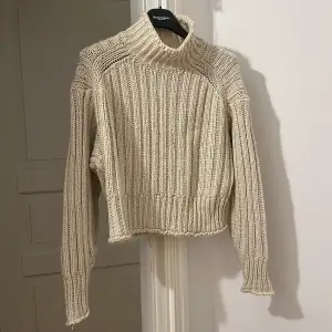 Säljer en supermysig beige stickad polotröja från H&M. Perfekt för kyliga dagar med sin höga krage och långa ärmar. Tröjan är croppad och har en ribbad design som ger en snygg look. Passar perfekt till både jeans och kjol!