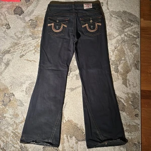 True Religion Bobby Woodstock bootcut jeans - True Religion Bobby Woodstock distressed jeans i strl 32W 34L, 27cm benöppning. De är svarta med en svag blå underton. De har lite heelbite men annars är de i perfekt skick! Köpta för 1200