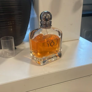 Stronger with you - Säljer en elegant parfymflaska med en rund silverkork. Flaskan är fylld med en gyllene doftvätska och har en stilren design. Perfekt för den som vill ha en lyxig touch på sin parfymhylla. 45ml kvar i flaskan.