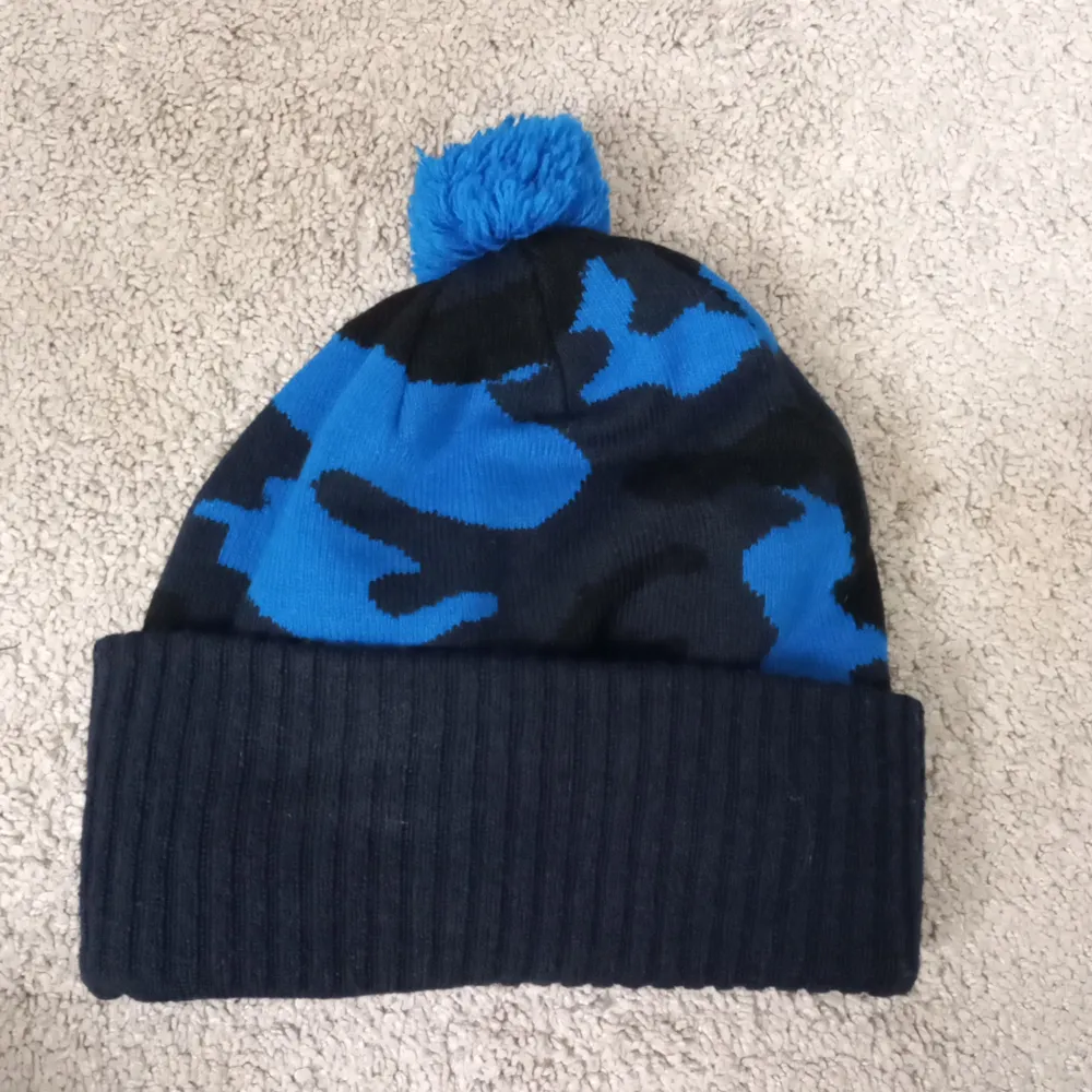 Säljer en cool mössa från Firefly i blått och svart med ett camouflagemönster. Den har en ribbad kant och en blå tofs på toppen. Perfekt för att hålla sig varm med stil under kalla dagar. Märket 'My Everyday Beanie' ger den en extra touch av street style. Är däremot nästan helt ny och pris 120kr. Asusteet.