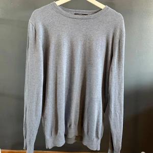 Ljusare blå stickad tröja - En tunn stickad blå tröja köpt från dressman. Storlek M som knappt är använd.  Funkar med en t-shirts under, bra en sommarkväll men även höst dagar.