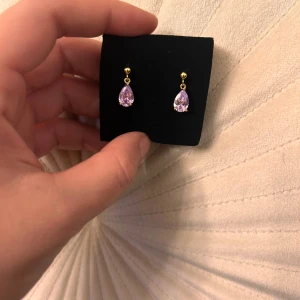 Droppformade örhängen med lila sten  - Eleganta droppformade örhängen med lila sten. 