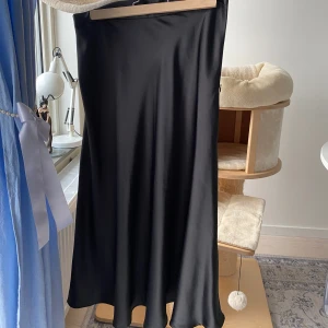 Satin kjol - Svart kjol i station material. Jag är 163 och den är ner till anklarna på mig